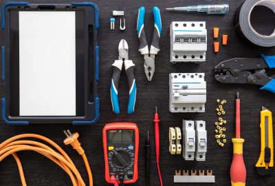 Flat lay composition with electrical tools and digital tablet on wooden background.